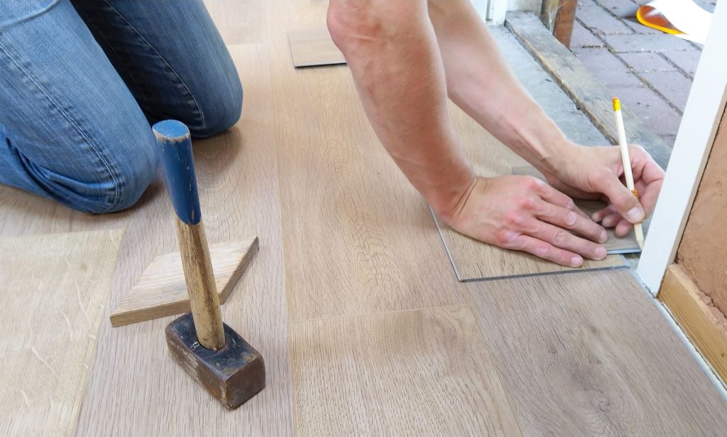 Mains mesurant et marquant des lames de parquet avant la découpe
