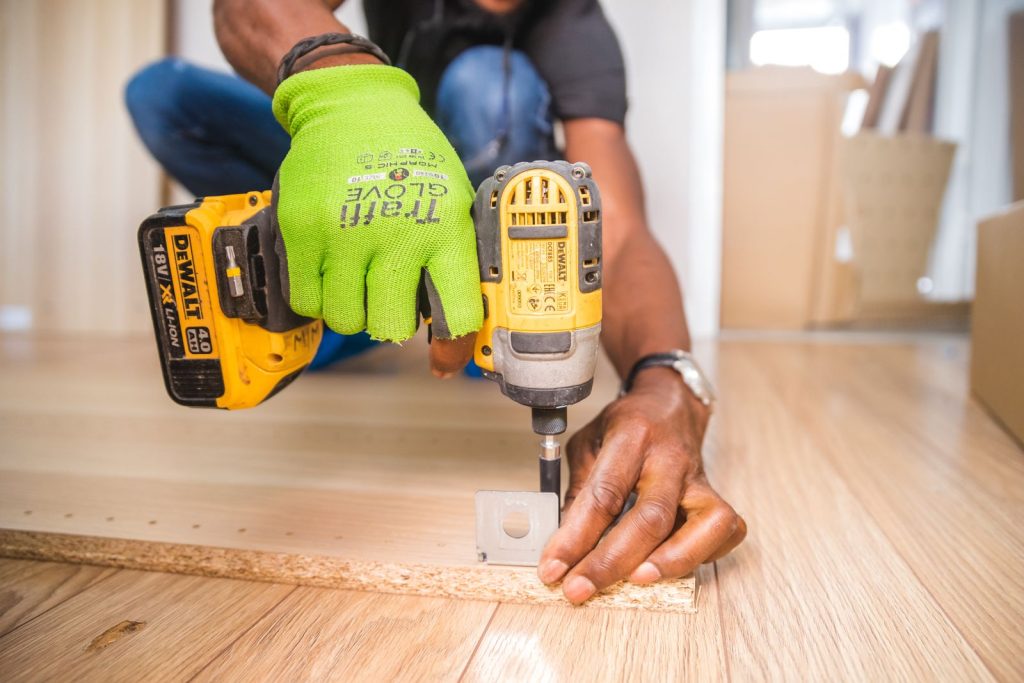 Main utilisant une perceuse pour des travaux de rénovation sur un sol en bois