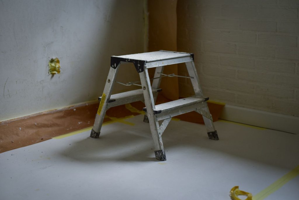 Escabeau posé dans une pièce en travaux, sol protégé avant la pose