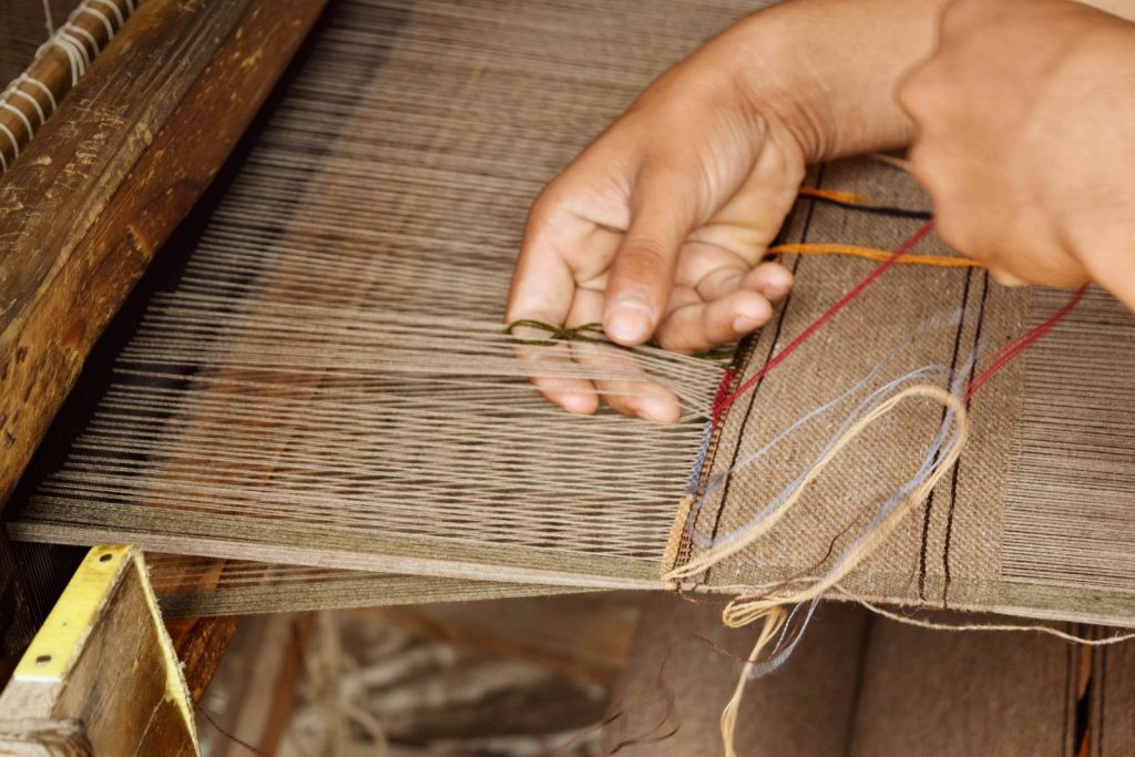 Mains tissant un tapis fait main sur un métier à tisser traditionnel