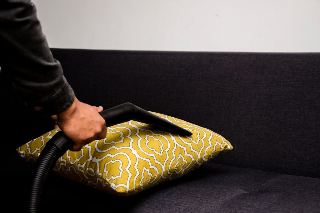 Gros plan d'un aspirateur nettoyant un coussin sur un canapé