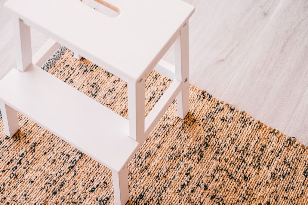 Tapis en jute naturel posé sous un tabouret blanc
