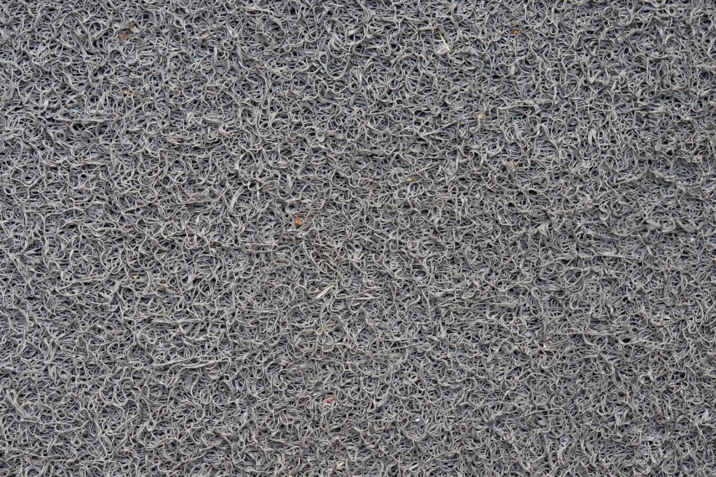 Tapis d’entrée gris texturé posé au sol pour capter salissures et humidité