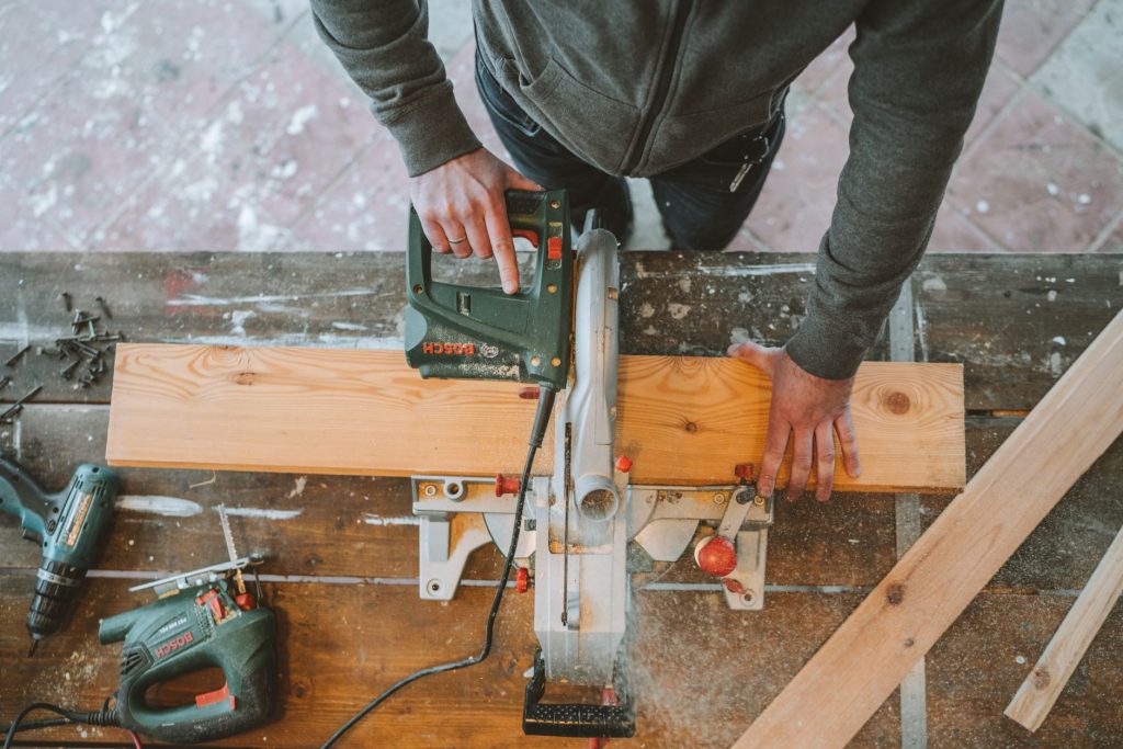 Artisan découpant une planche de bois à la scie sur un chantier