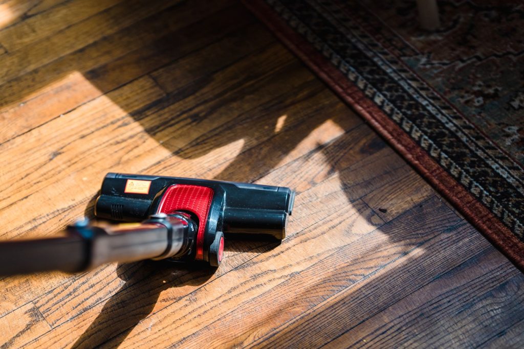 Aspirateur passant sur un sol en bois près d'un tapis
