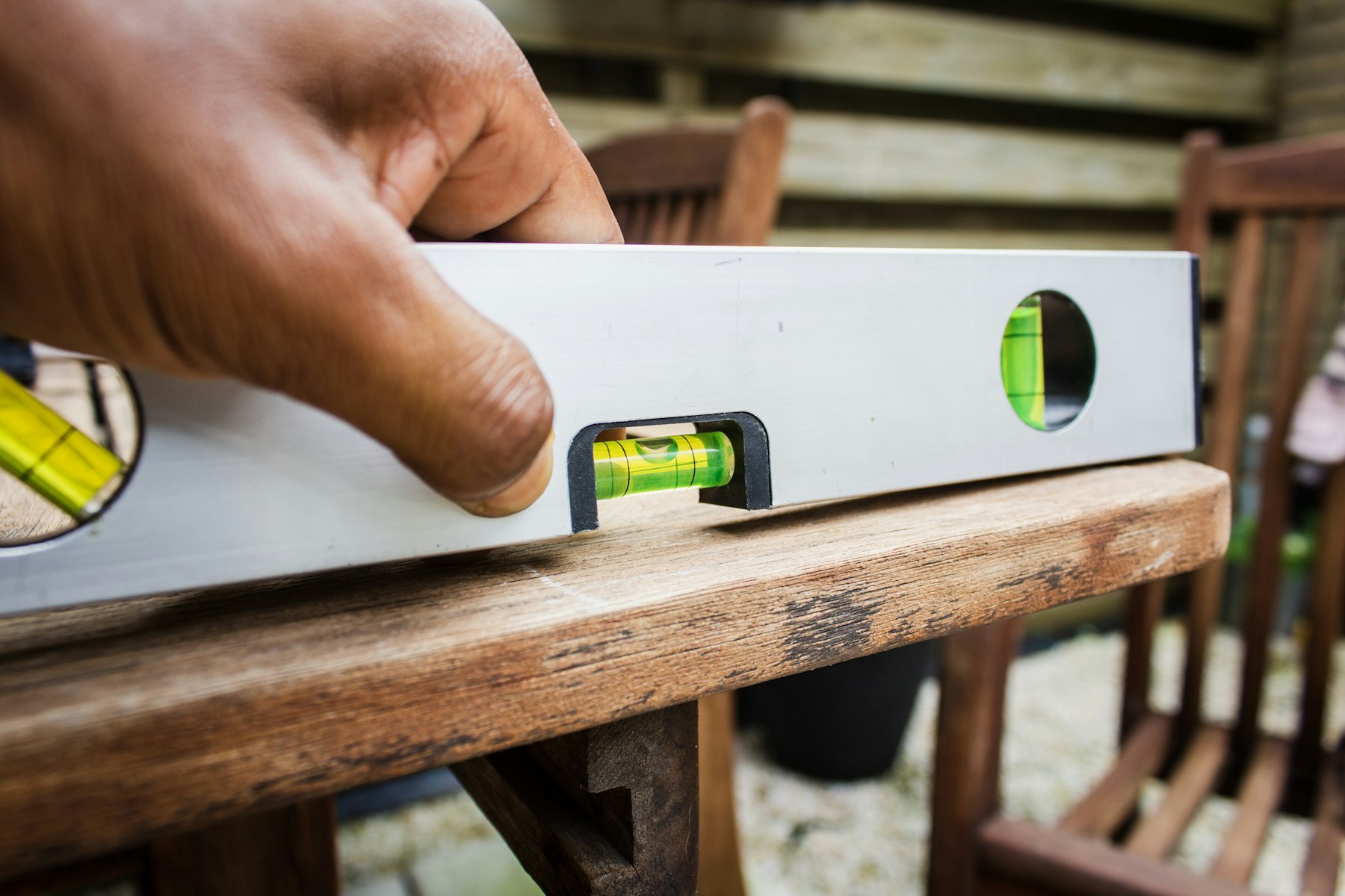 niveau à bulle posé sur une planche de bois, main qui règle l'outil